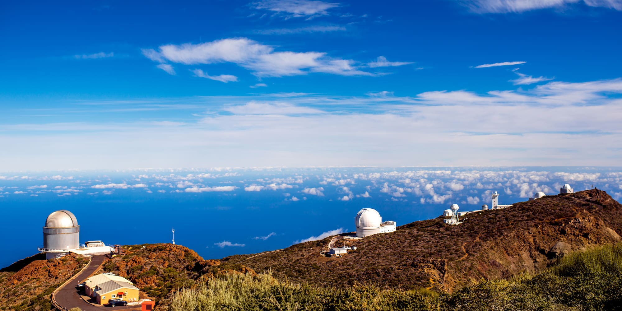 a view of a mountain with buildings and clouds in the sky
