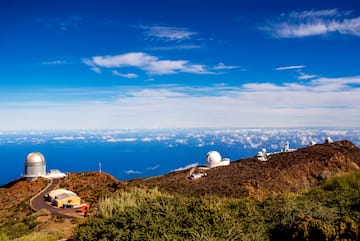 a view of a mountain with buildings and clouds in the sky