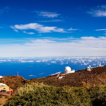 a view of a mountain with buildings and clouds in the sky