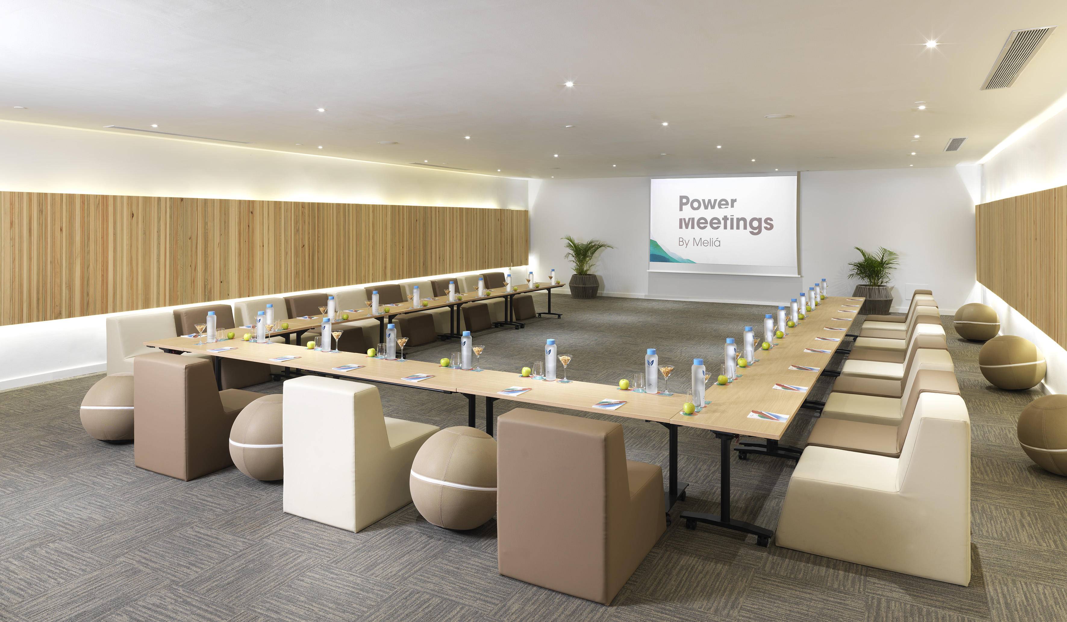 U-shaped meeting room with projector, modern chairs, wooden walls, drinks.