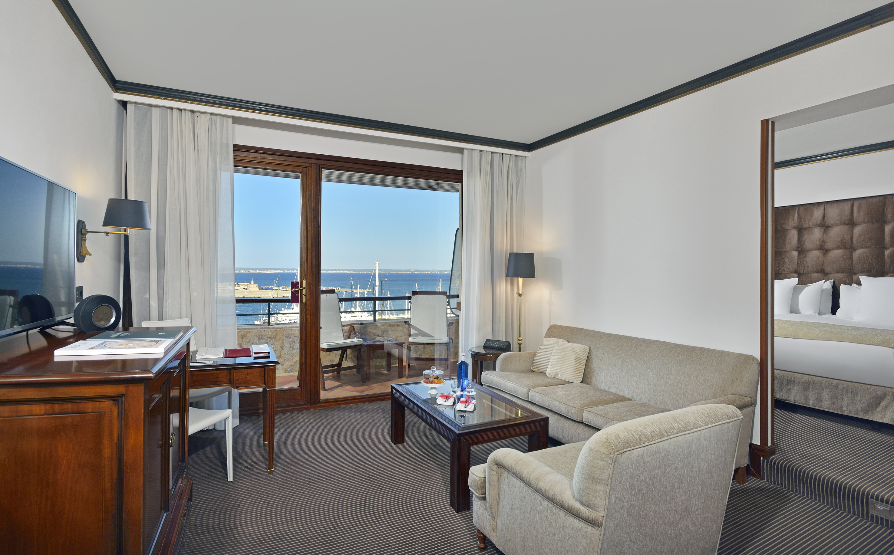 Hotel suite living room with marina view balcony, sofa, and bedroom.