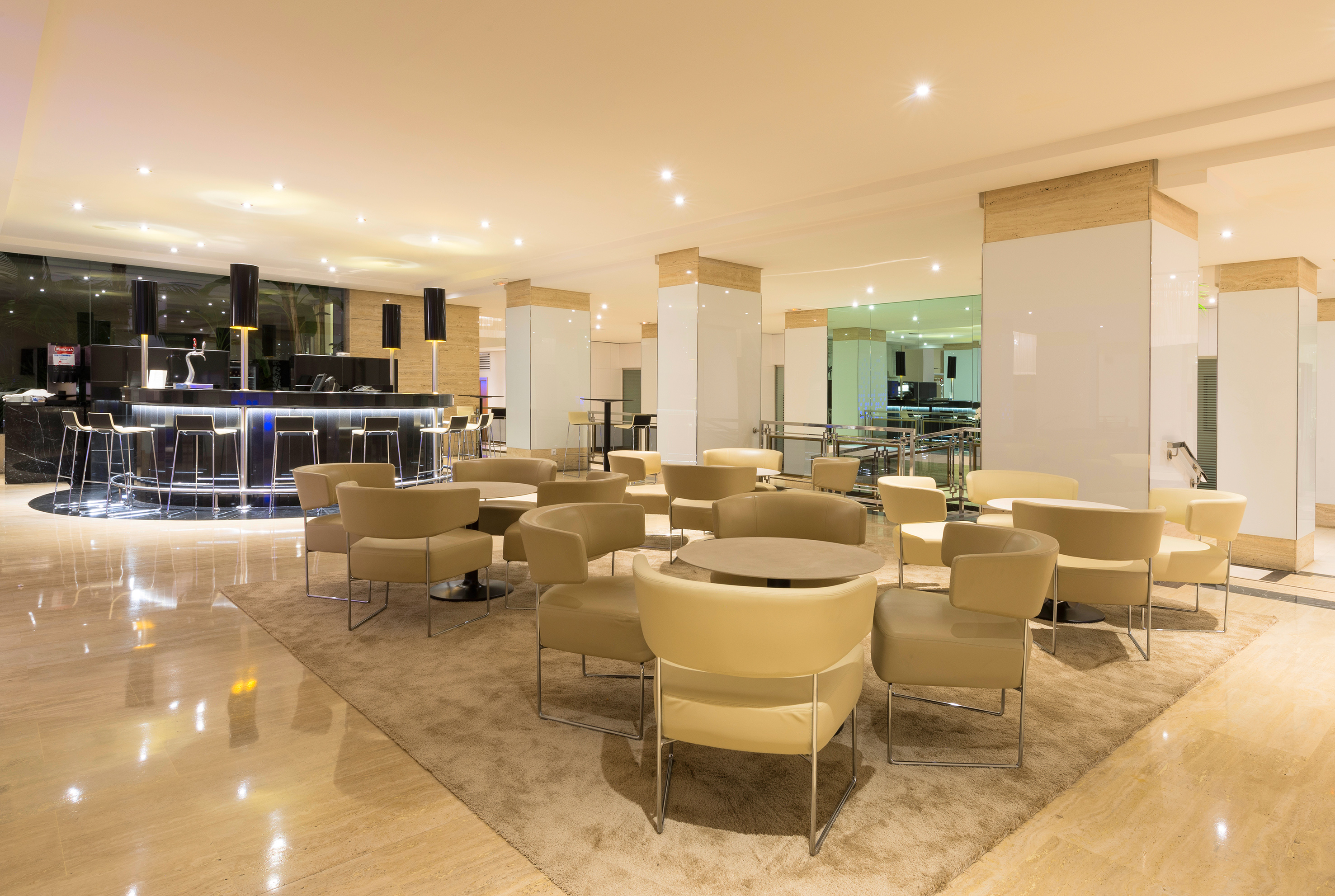 Modern hotel lobby lounge with sleek bar, beige seating, and polished floors.