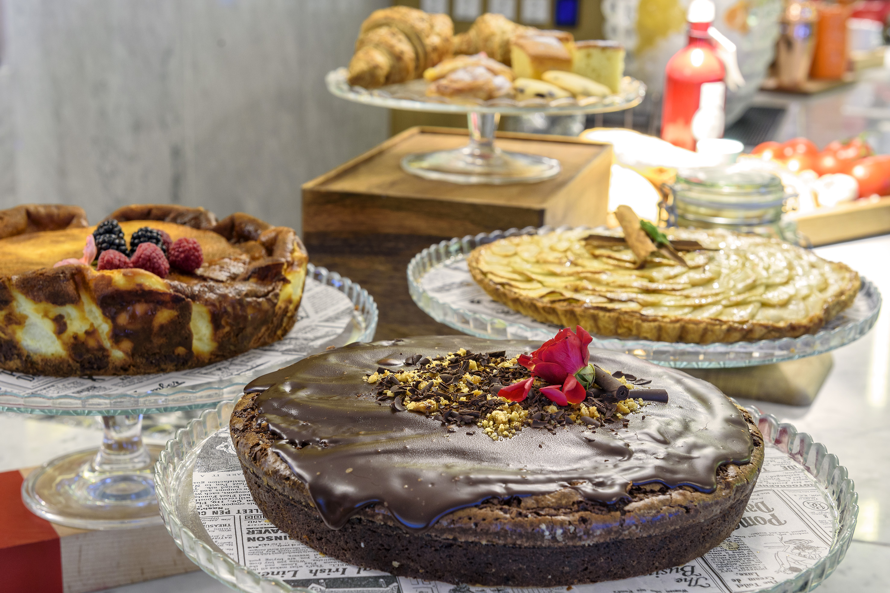 Bakery display of chocolate cake, berry cheesecake, apple tart, and pastries.