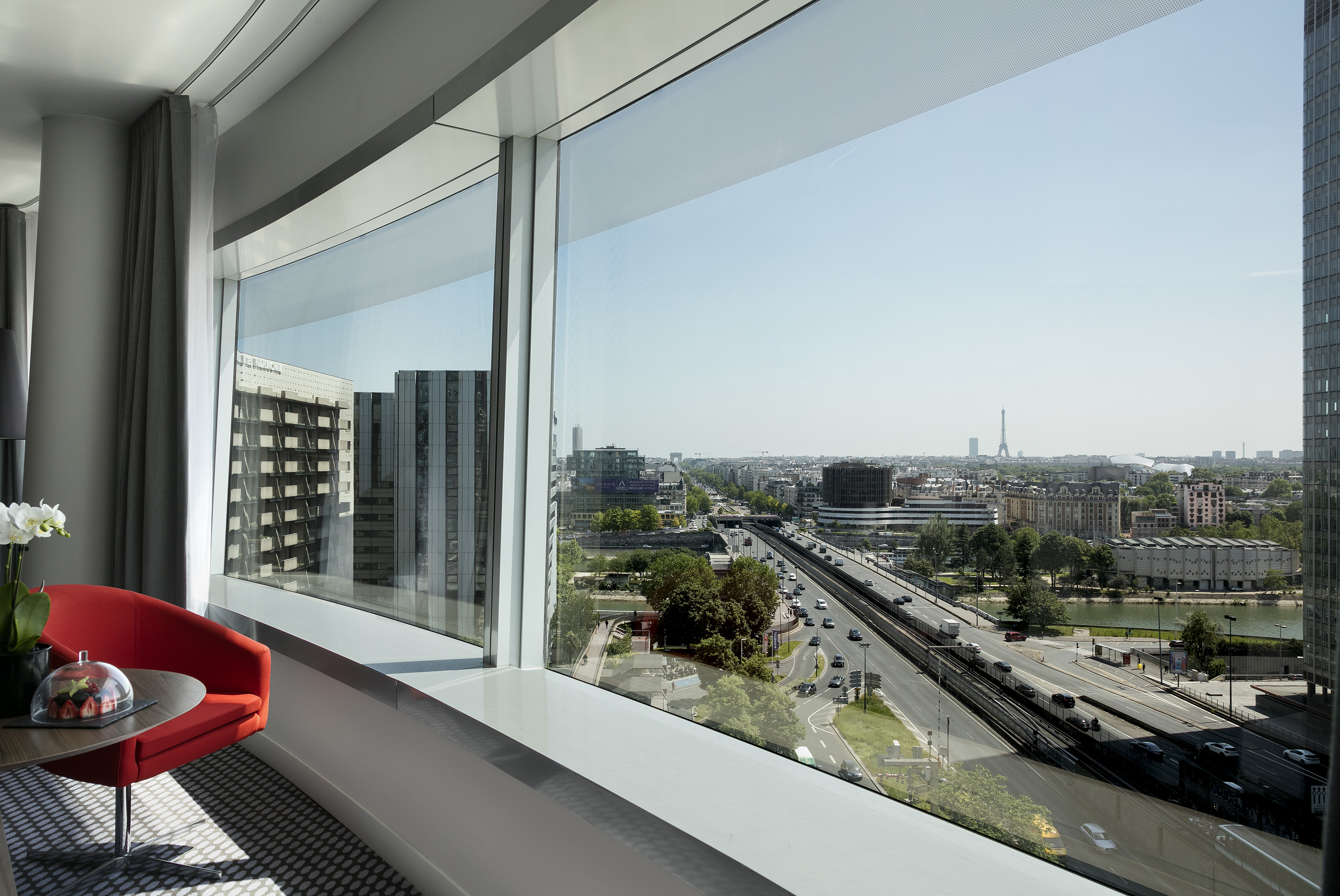 Modern hotel room overlooking Paris cityscape, Eiffel Tower, and busy road.