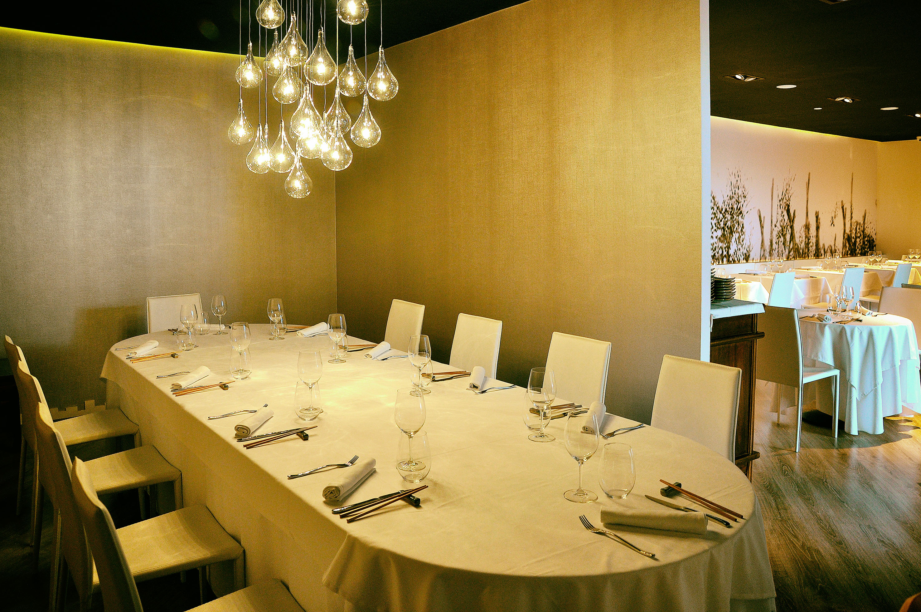 Modern dining room with long table set, white chairs, and droplet chandelier.