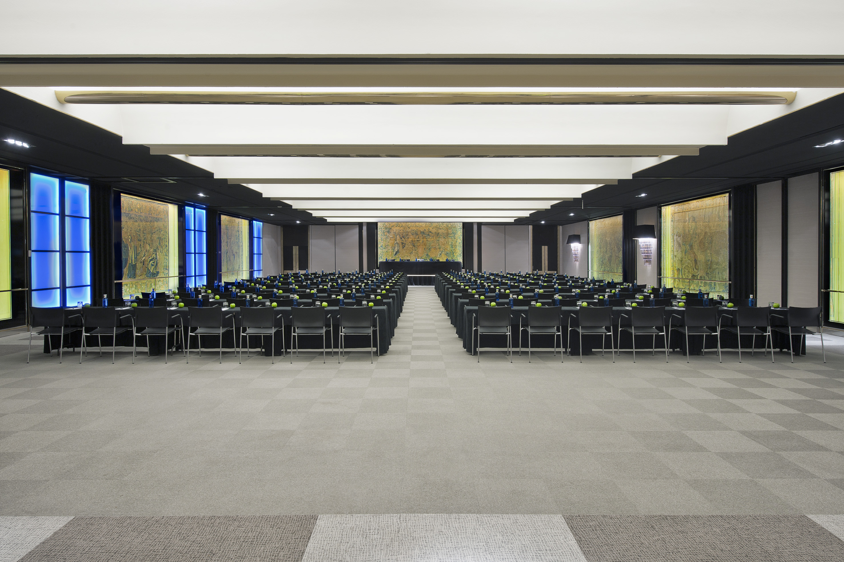 Spacious corporate event room with tables, chairs, and illuminated wall decor.