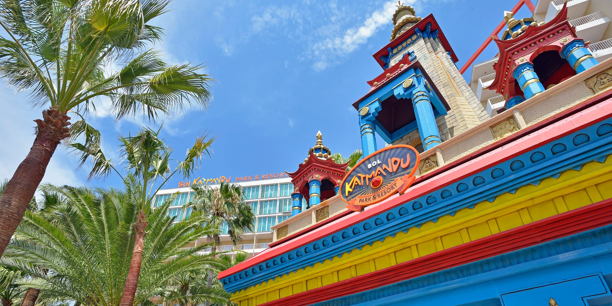 a colorful building with a tower and palm trees