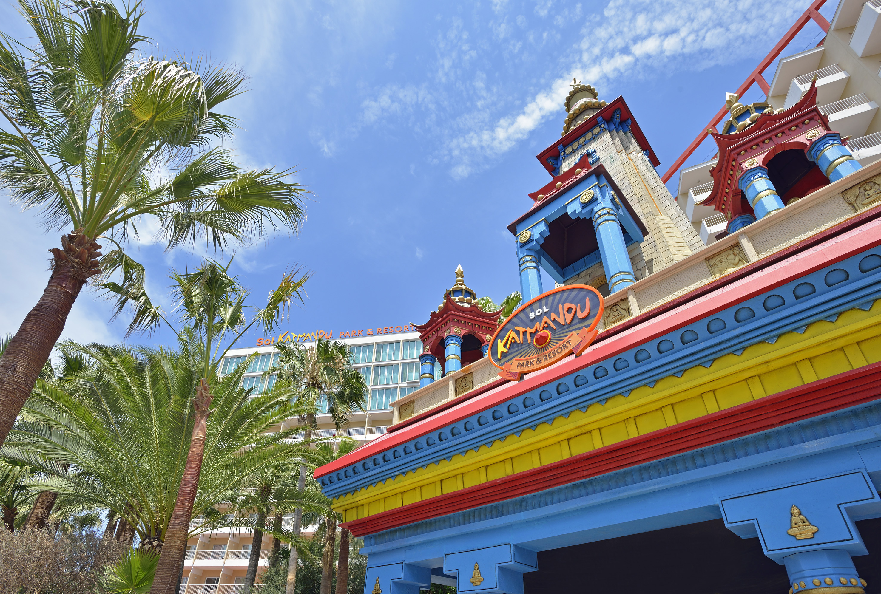 Sol Katmandu Park & Resort entrance with colorful building and palm trees.