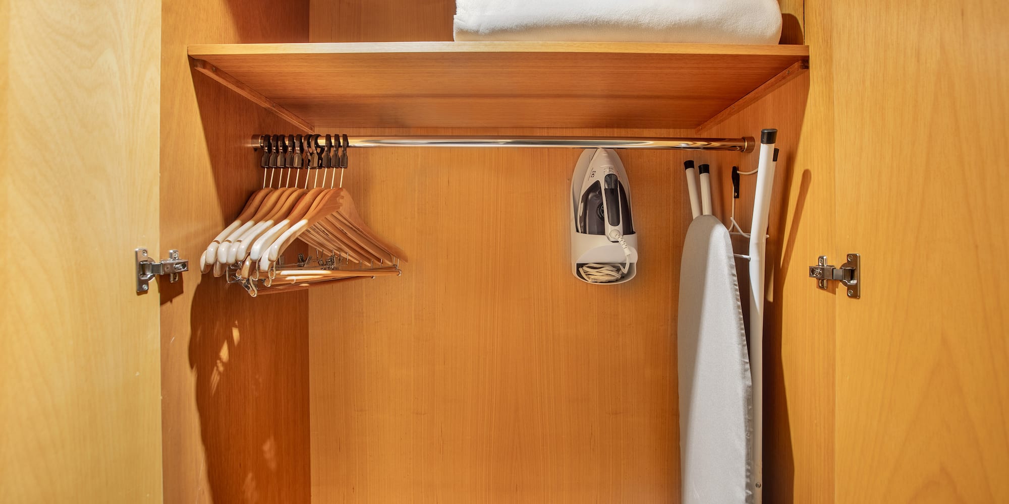 a closet with ironing board and swingers