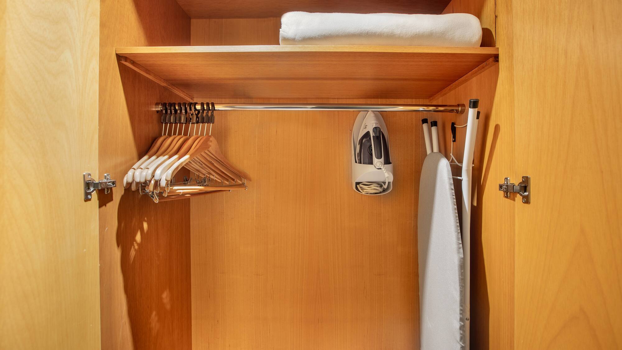 a closet with ironing board and swingers