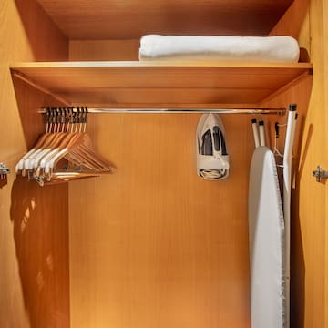 a closet with ironing board and swingers