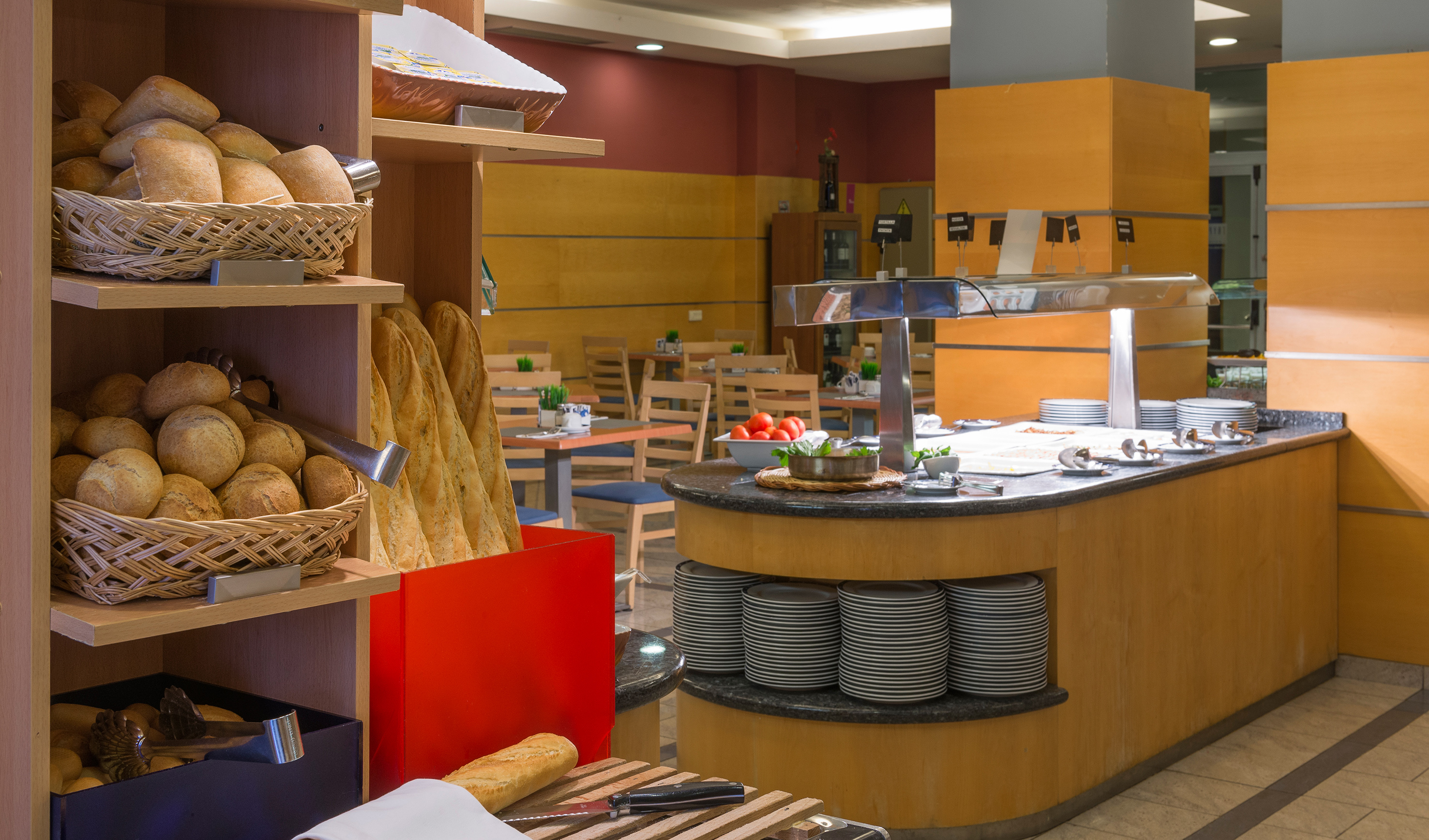 Hotel buffet dining area featuring fresh bread baskets and food stations.