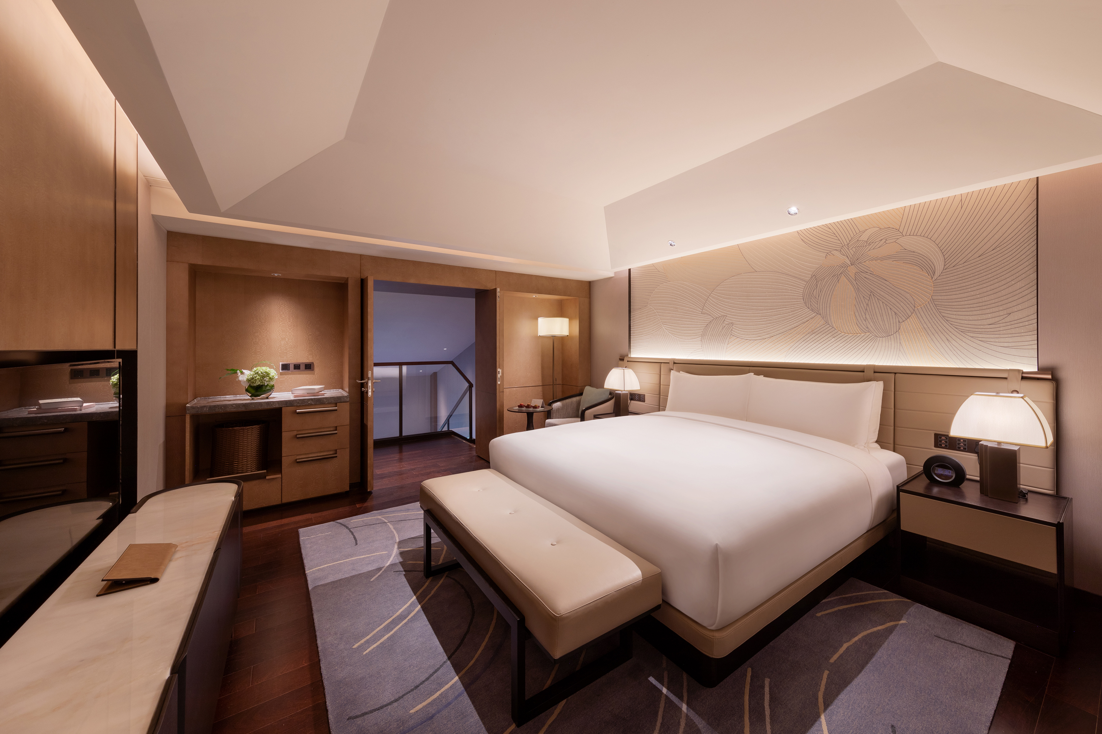 Luxury hotel bedroom with king bed, modern wood paneling, and elegant wall art.