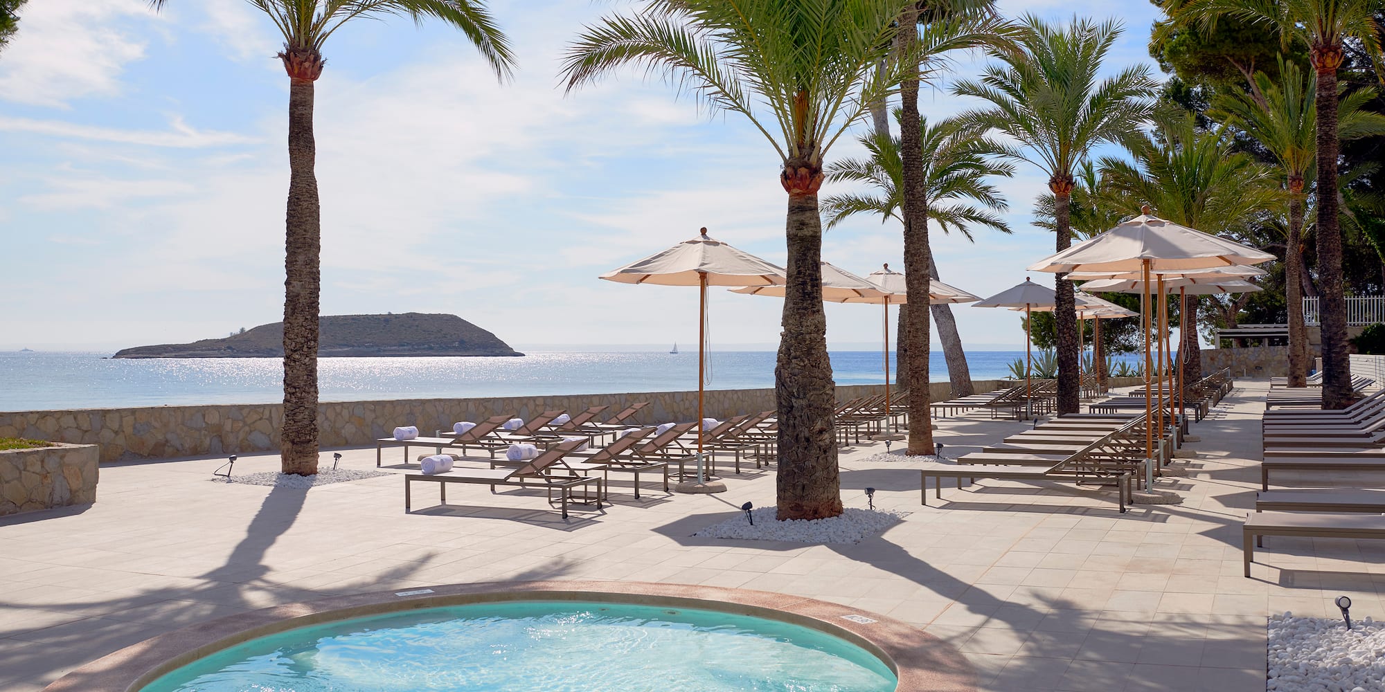 a pool with umbrellas and chairs on a beach