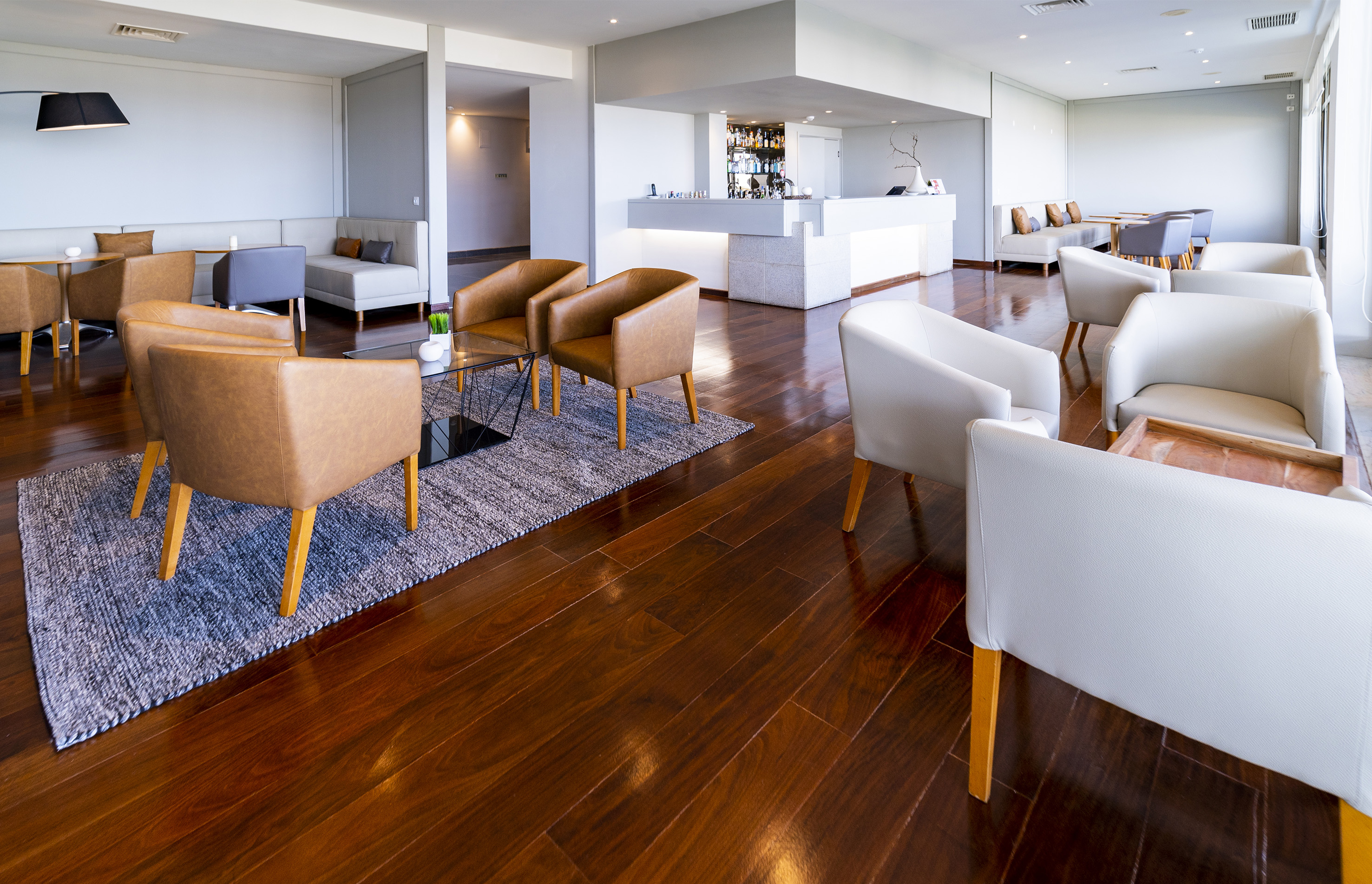Upscale hotel lounge with contemporary seating, dark wood floor, and bar.
