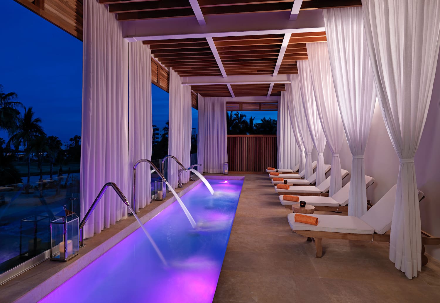 a pool with purple lights and white curtains