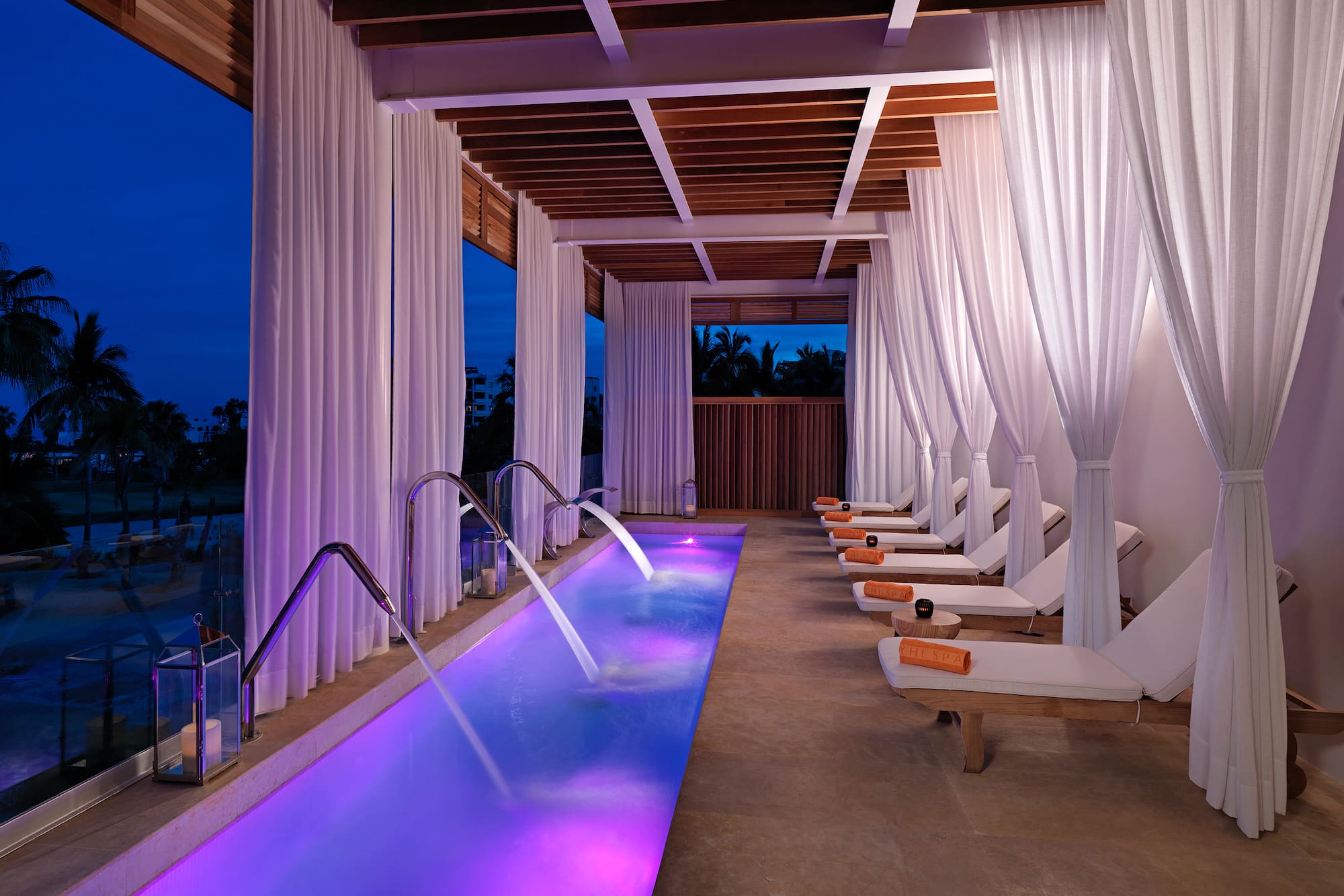 a pool with purple lights and white curtains