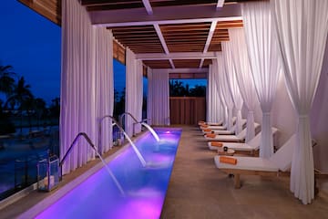 a pool with purple lights and white curtains
