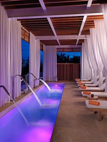 a pool with purple lights and white curtains