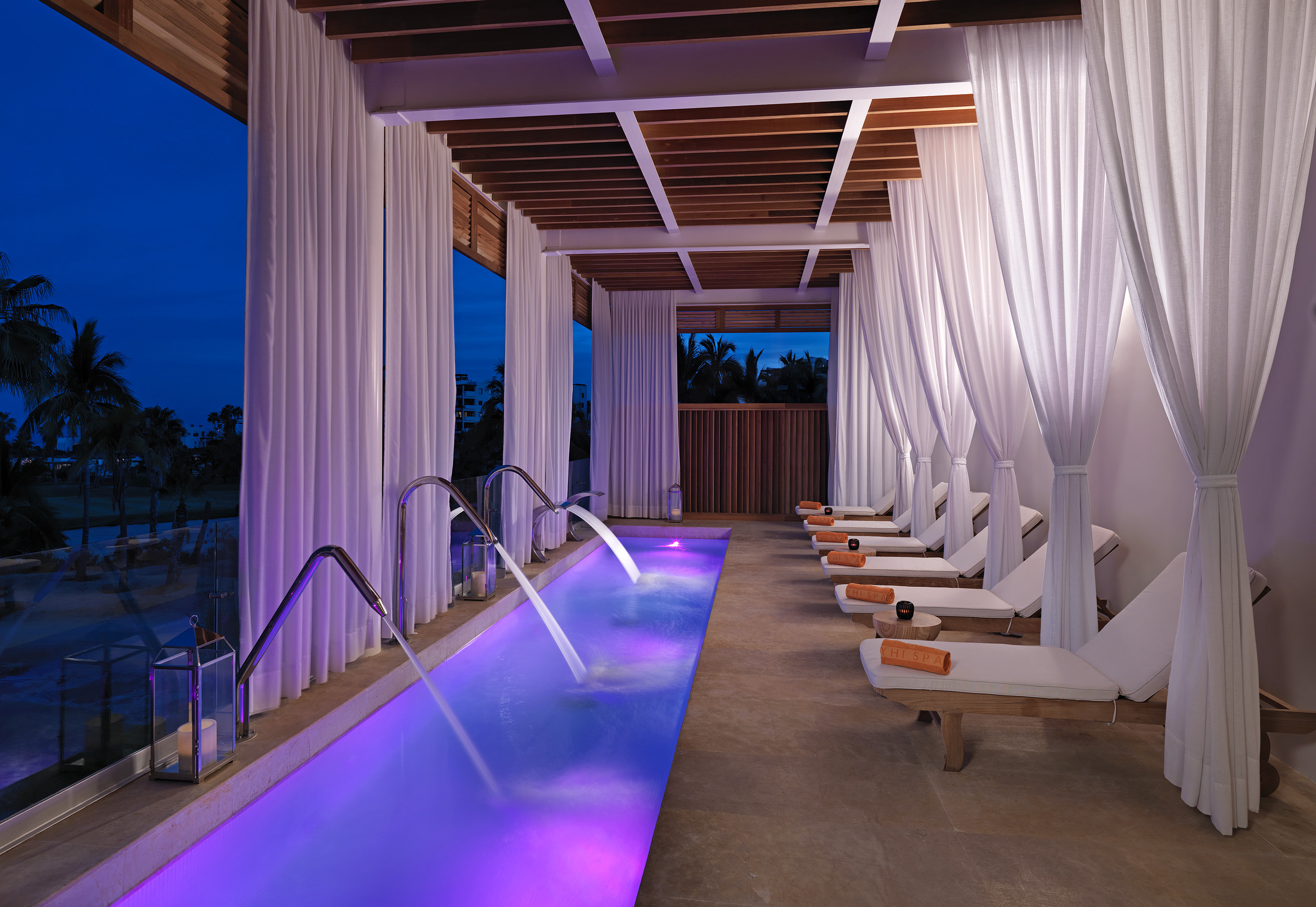 a pool with purple lights and white curtains