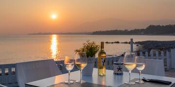 a table with wine glasses and a bottle on it by a body of water