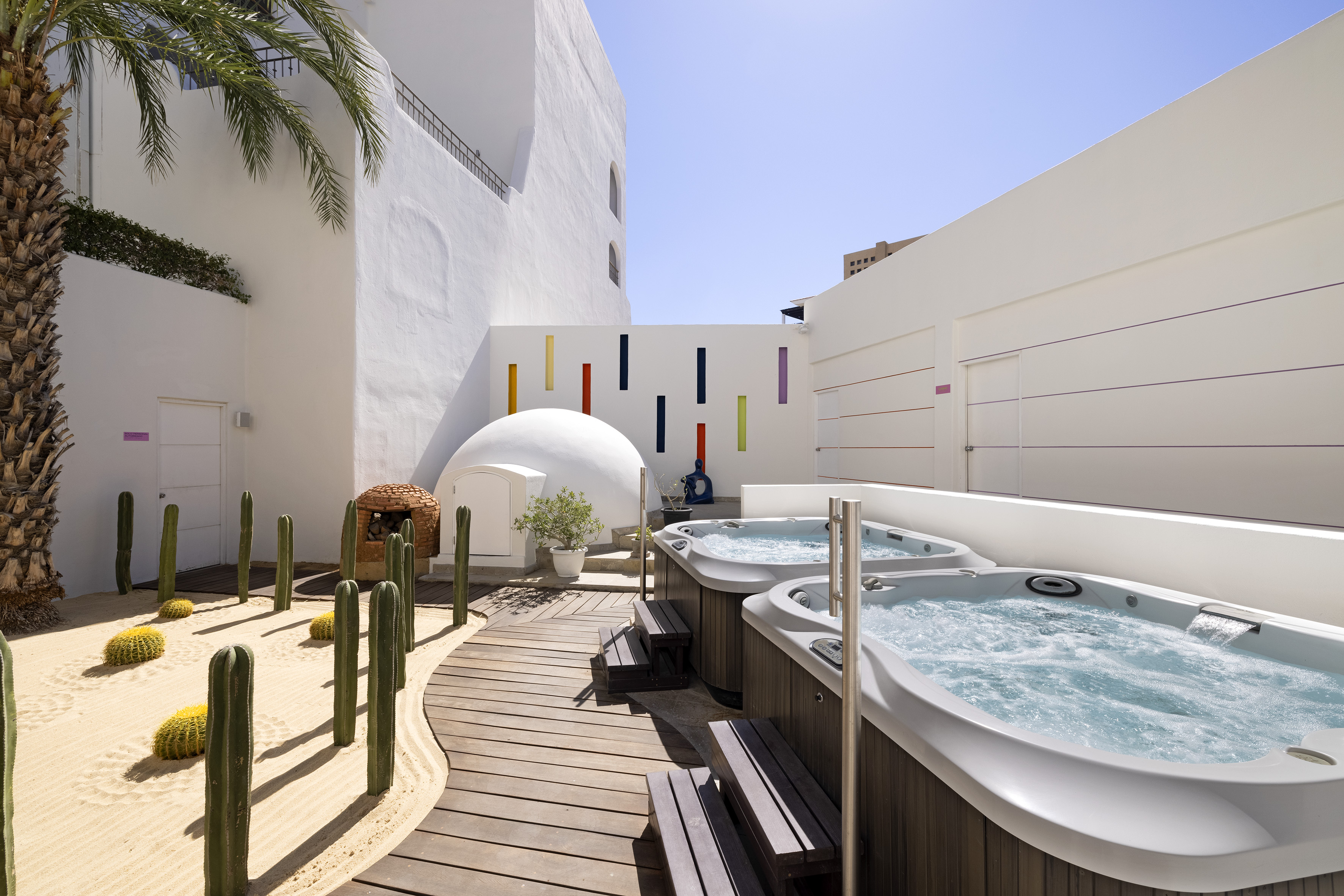 Resort outdoor spa with jacuzzis, desert garden, and minimalist white architecture.