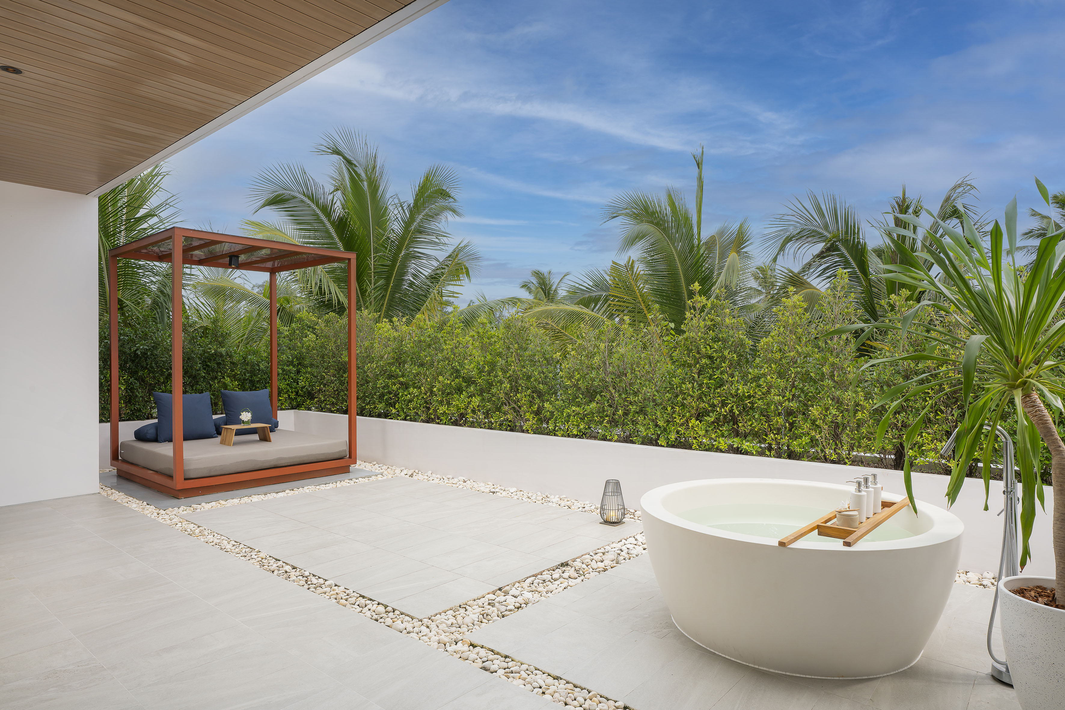 Luxury outdoor bathtub and daybed on a tropical resort patio.