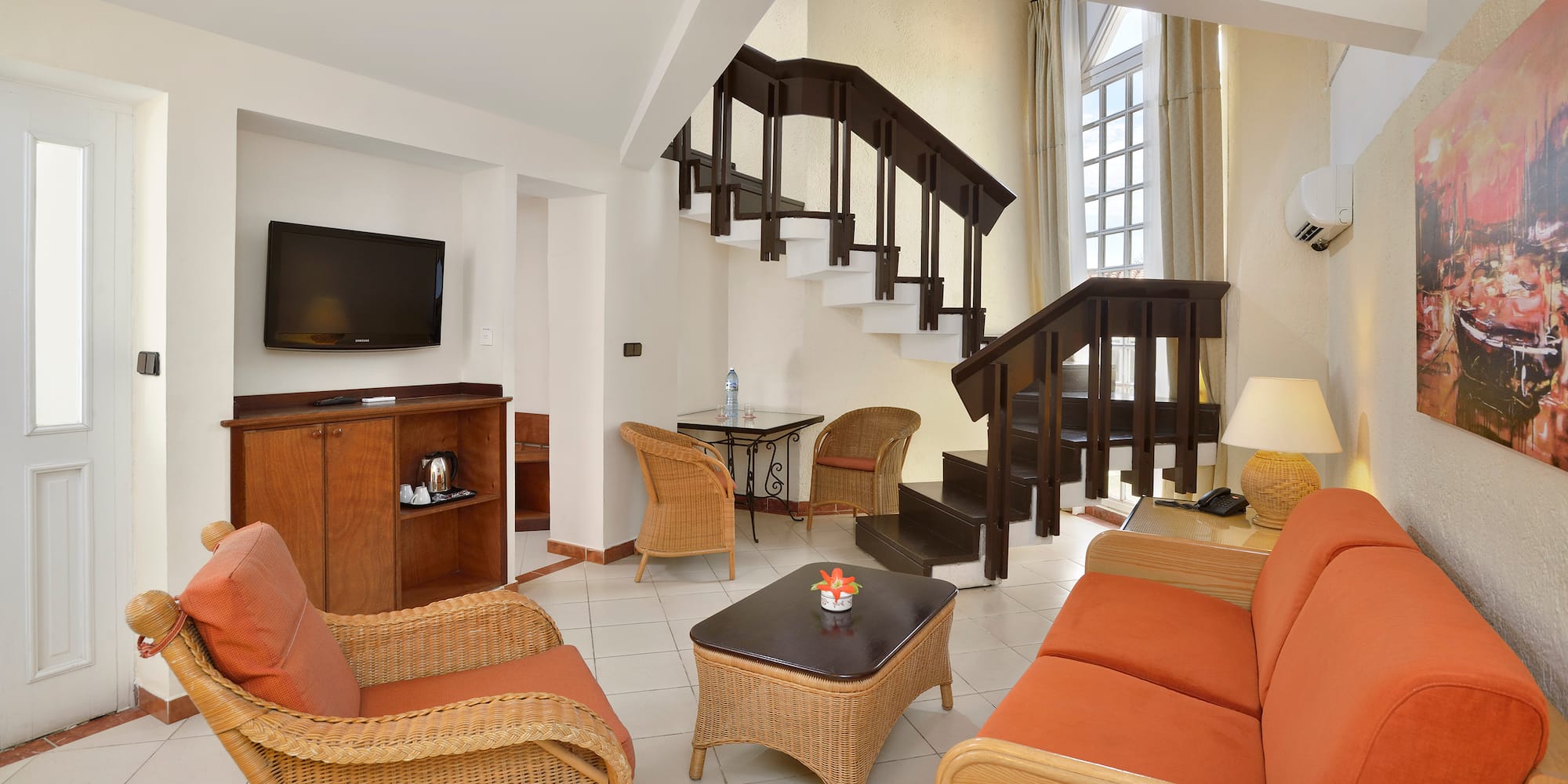 a room with a staircase and wicker furniture