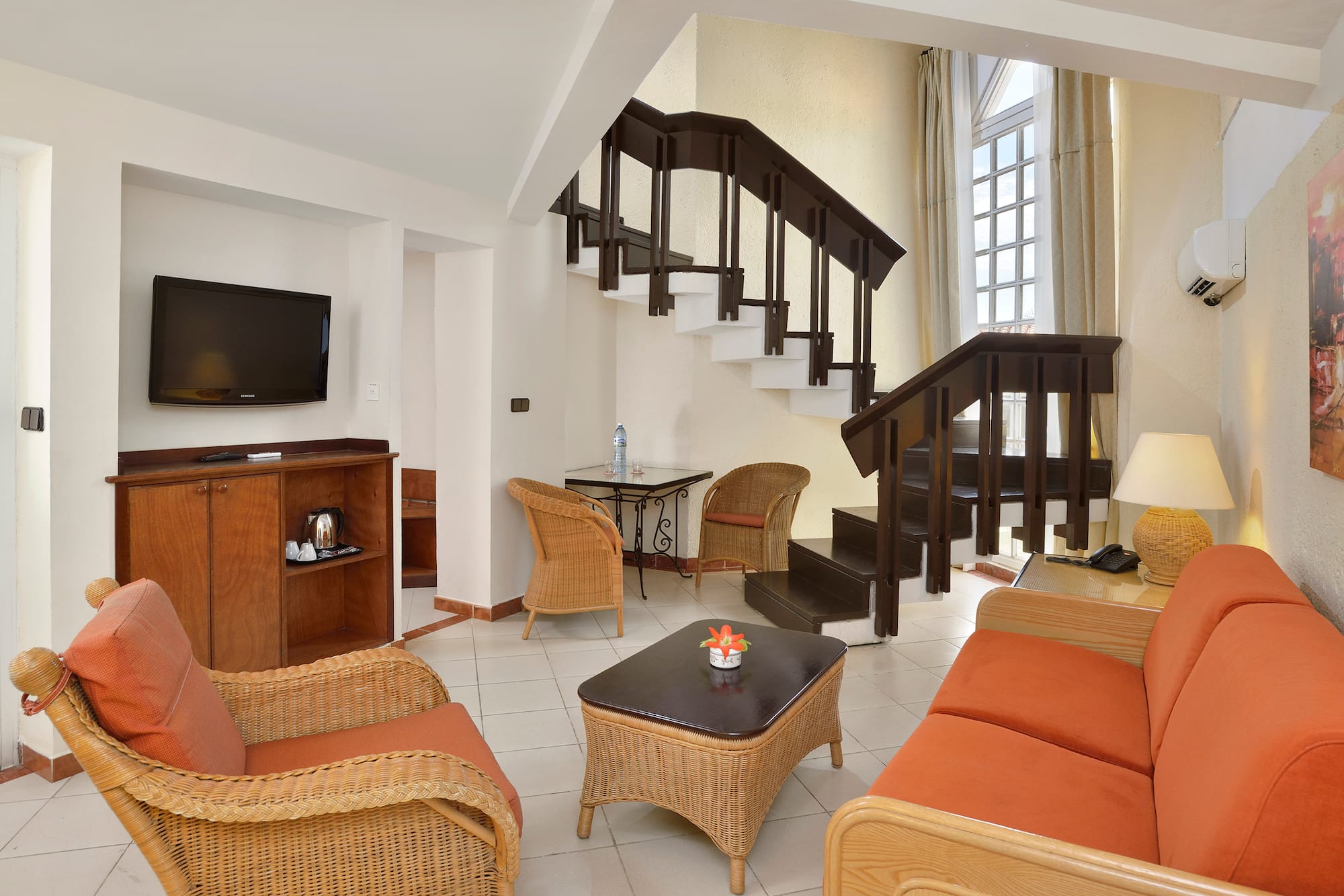 a room with a staircase and wicker furniture