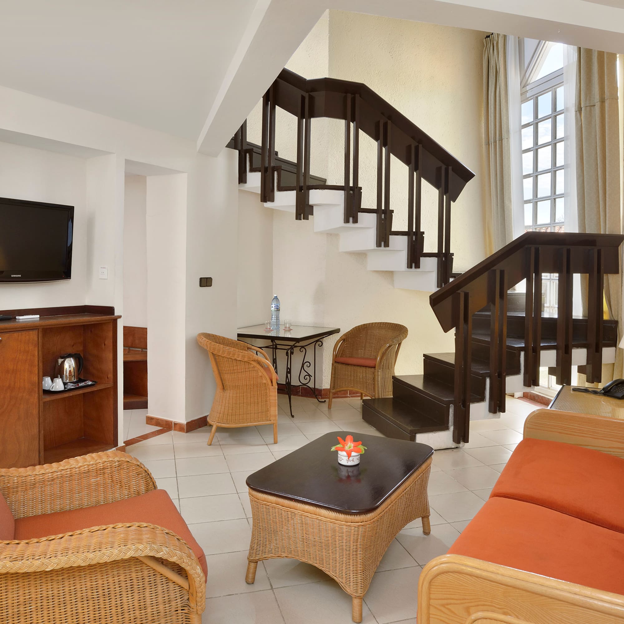 a room with a staircase and wicker furniture