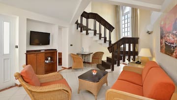 a room with a staircase and wicker furniture