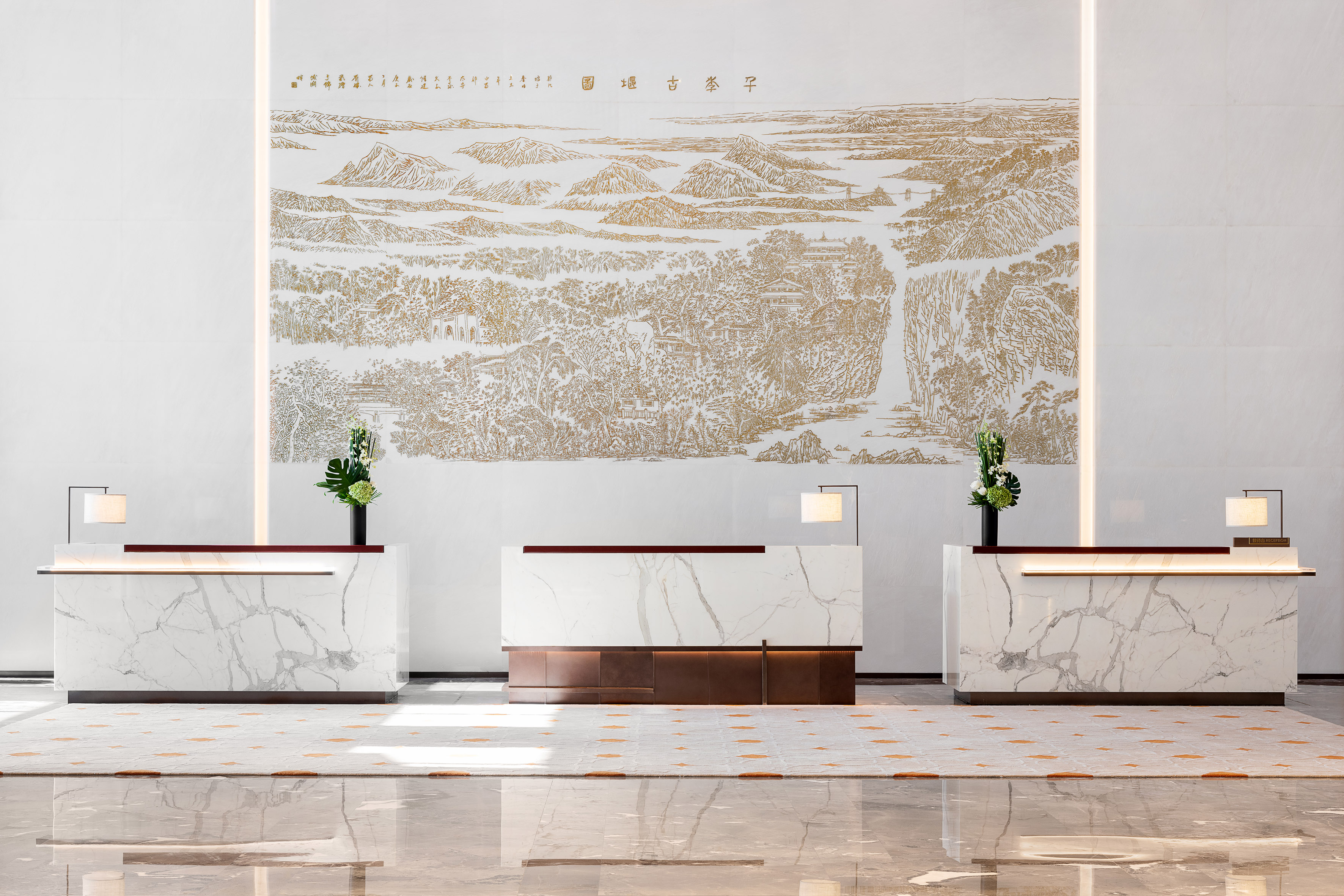 Hotel lobby with three marble reception desks and a golden landscape mural.