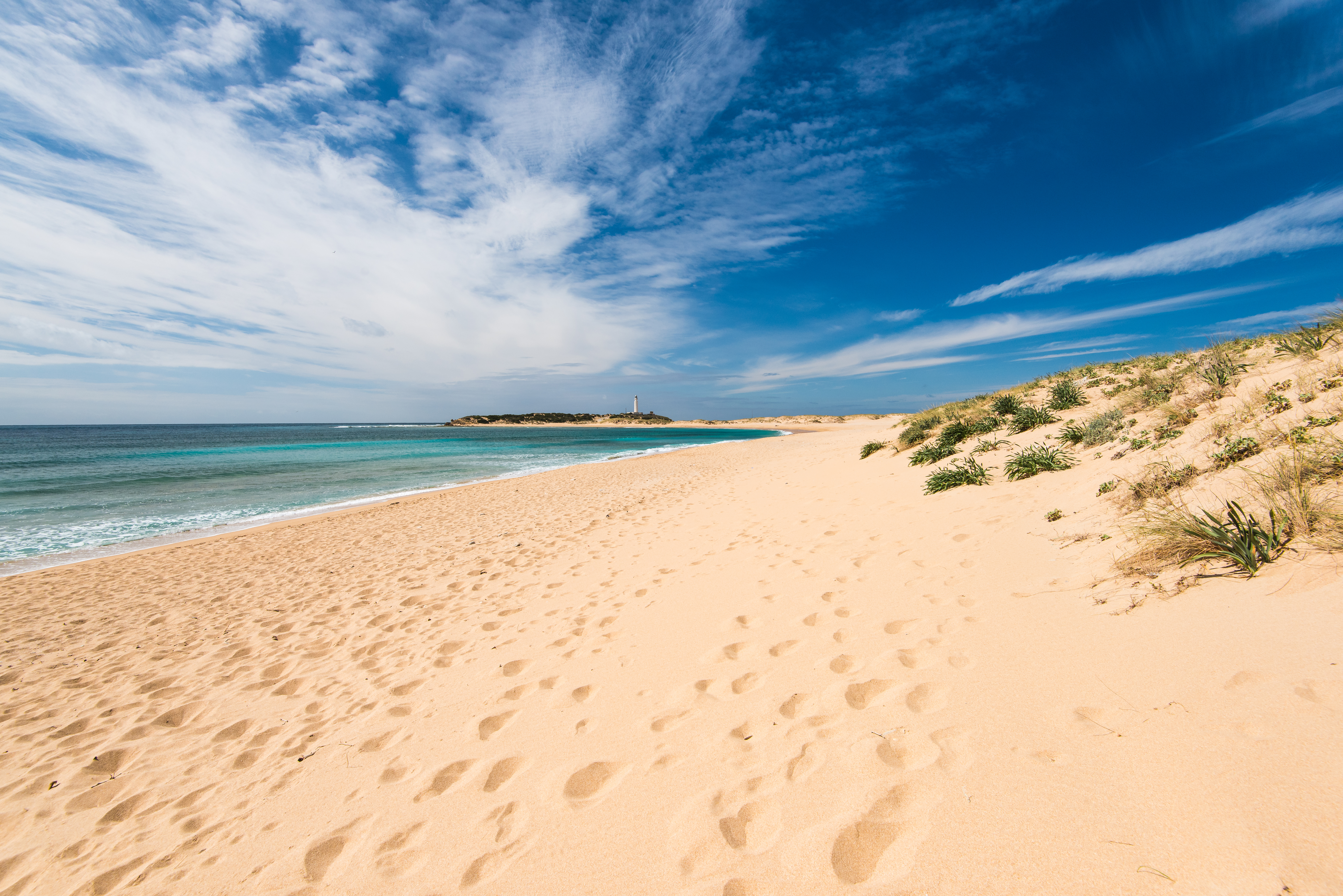 a sandy beach with blue water and blue sky