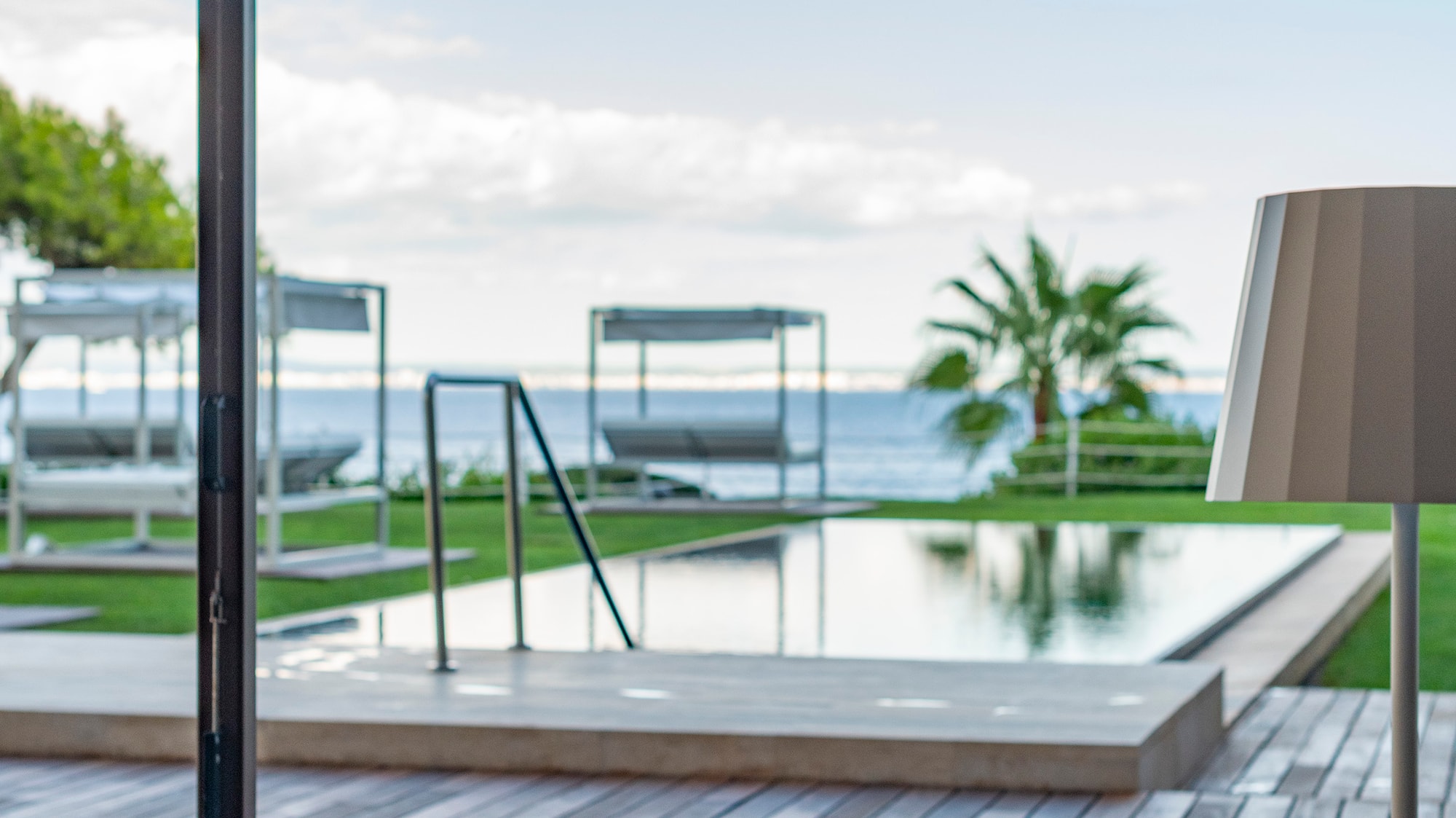 a table and chairs on a deck with a pool and a large umbrella