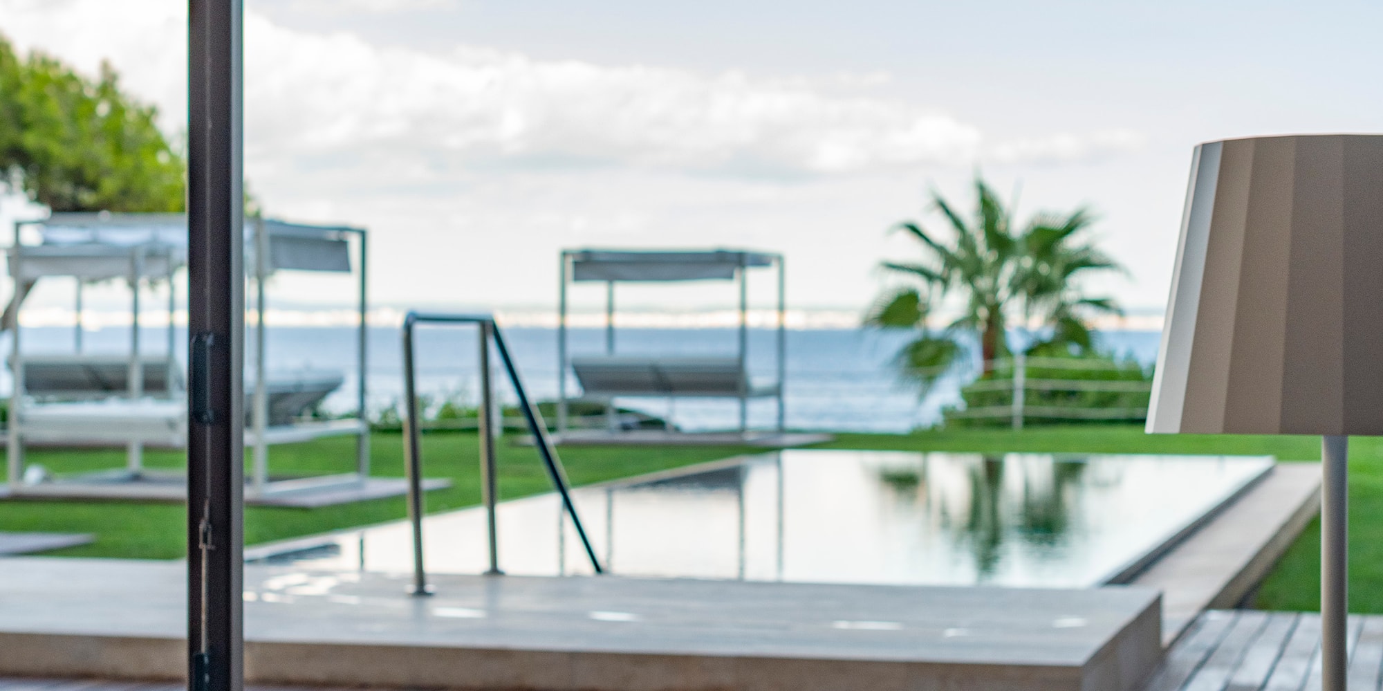 a table and chairs on a deck with a pool and a large umbrella
