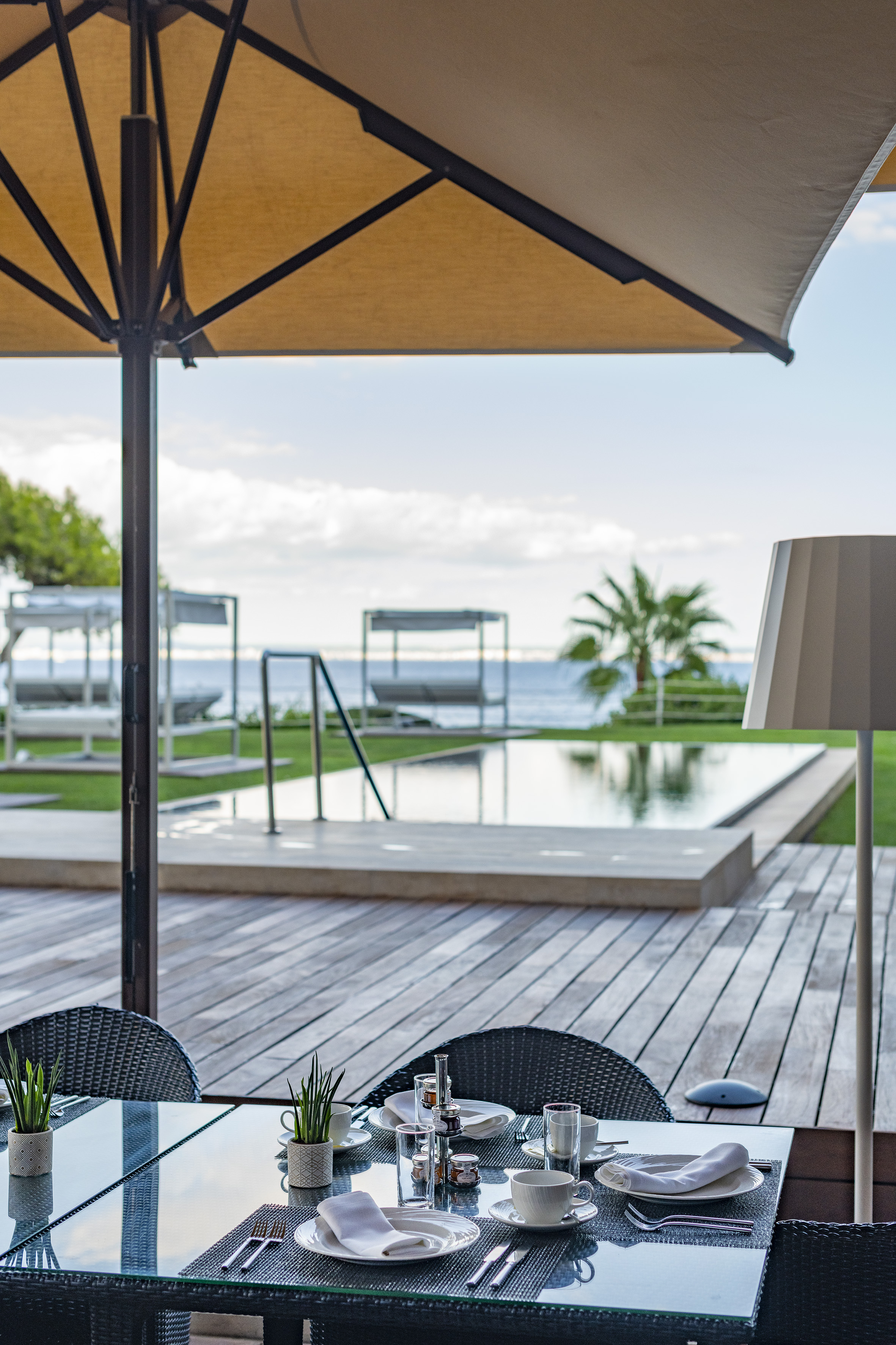 a table and chairs on a deck with a pool and a large umbrella