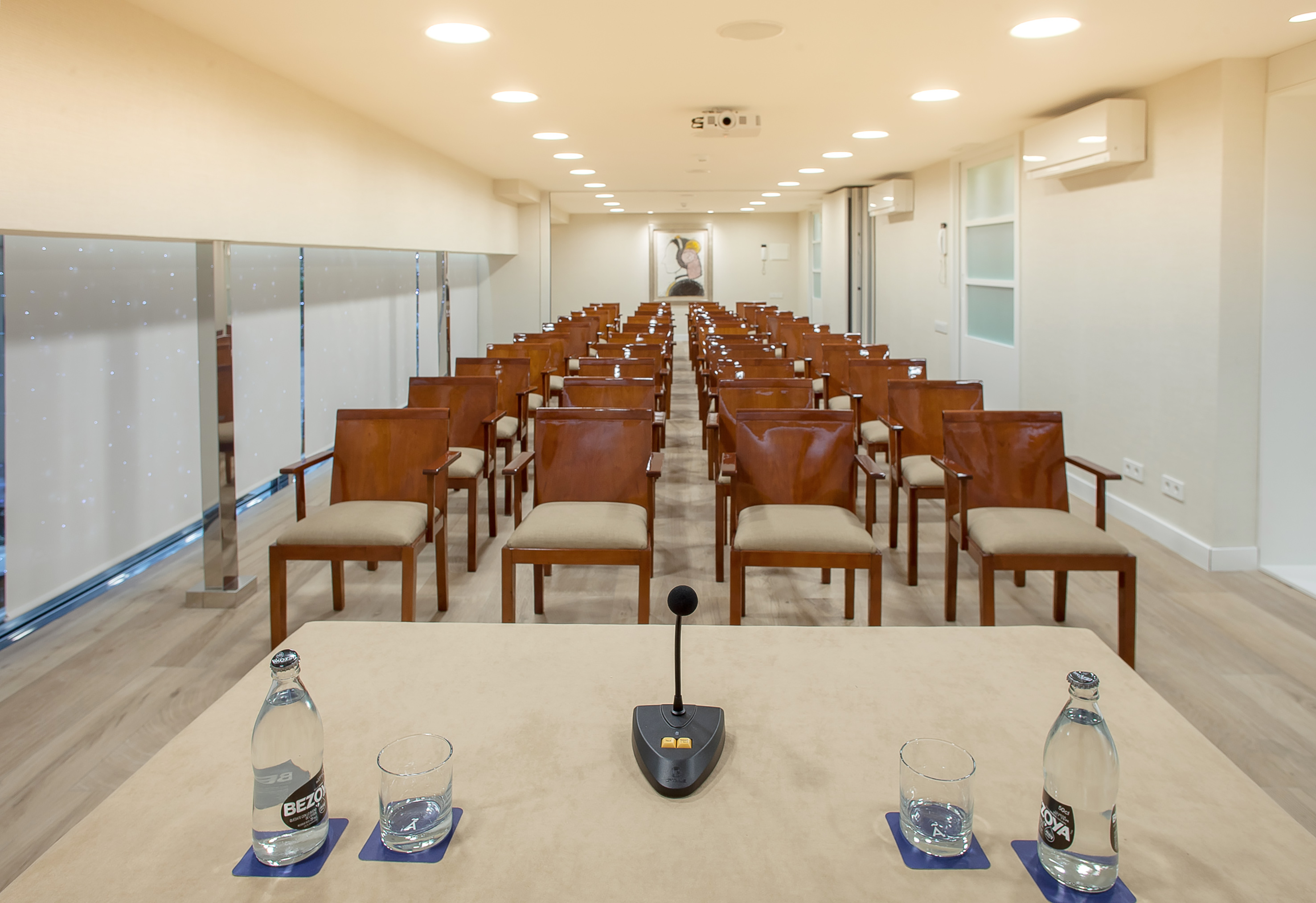 Modern empty conference room with rows of chairs, projector, and microphone.