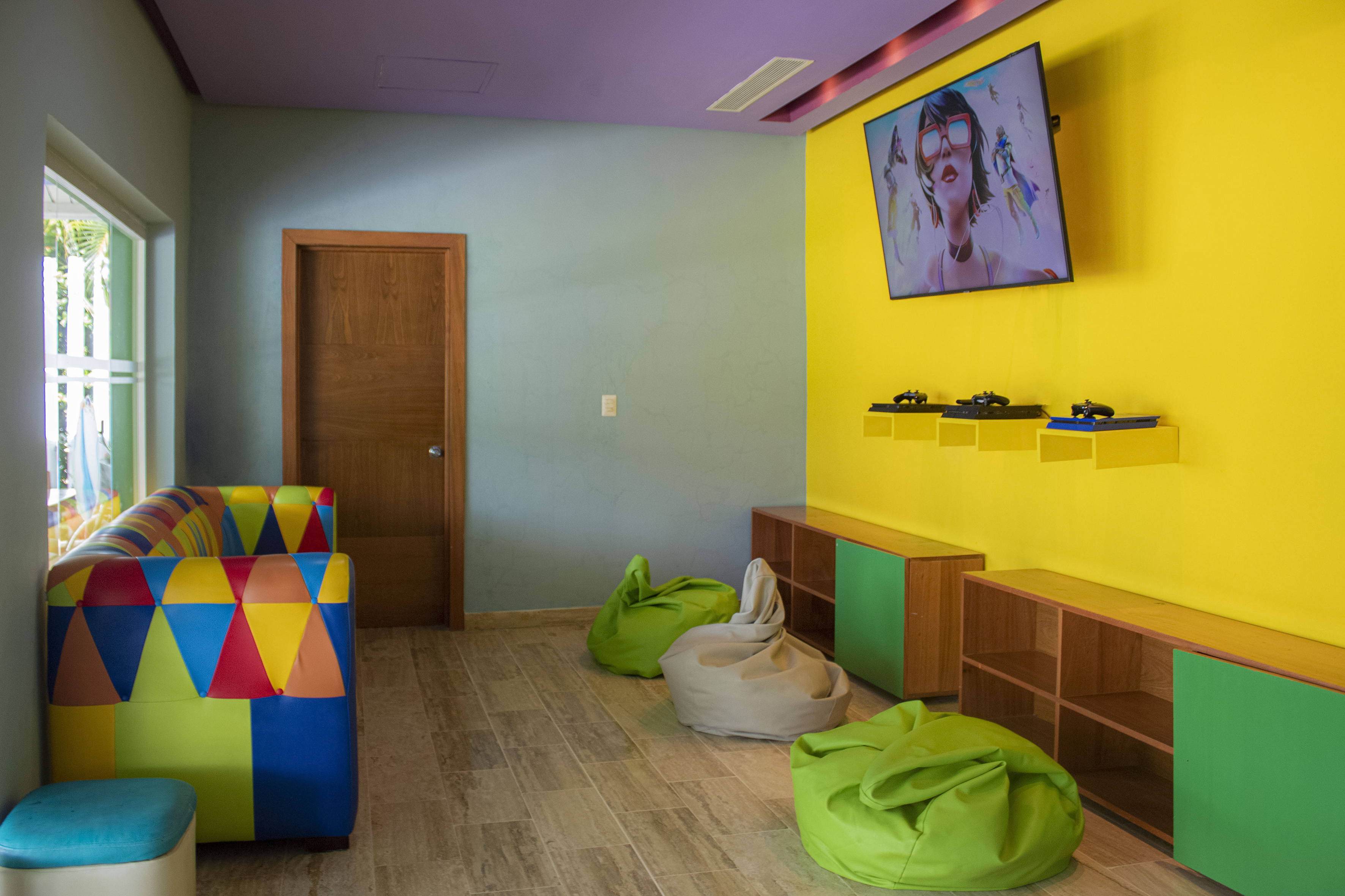 Vibrant kids game room with TV, gaming controllers, bean bags, and colorful sofa.