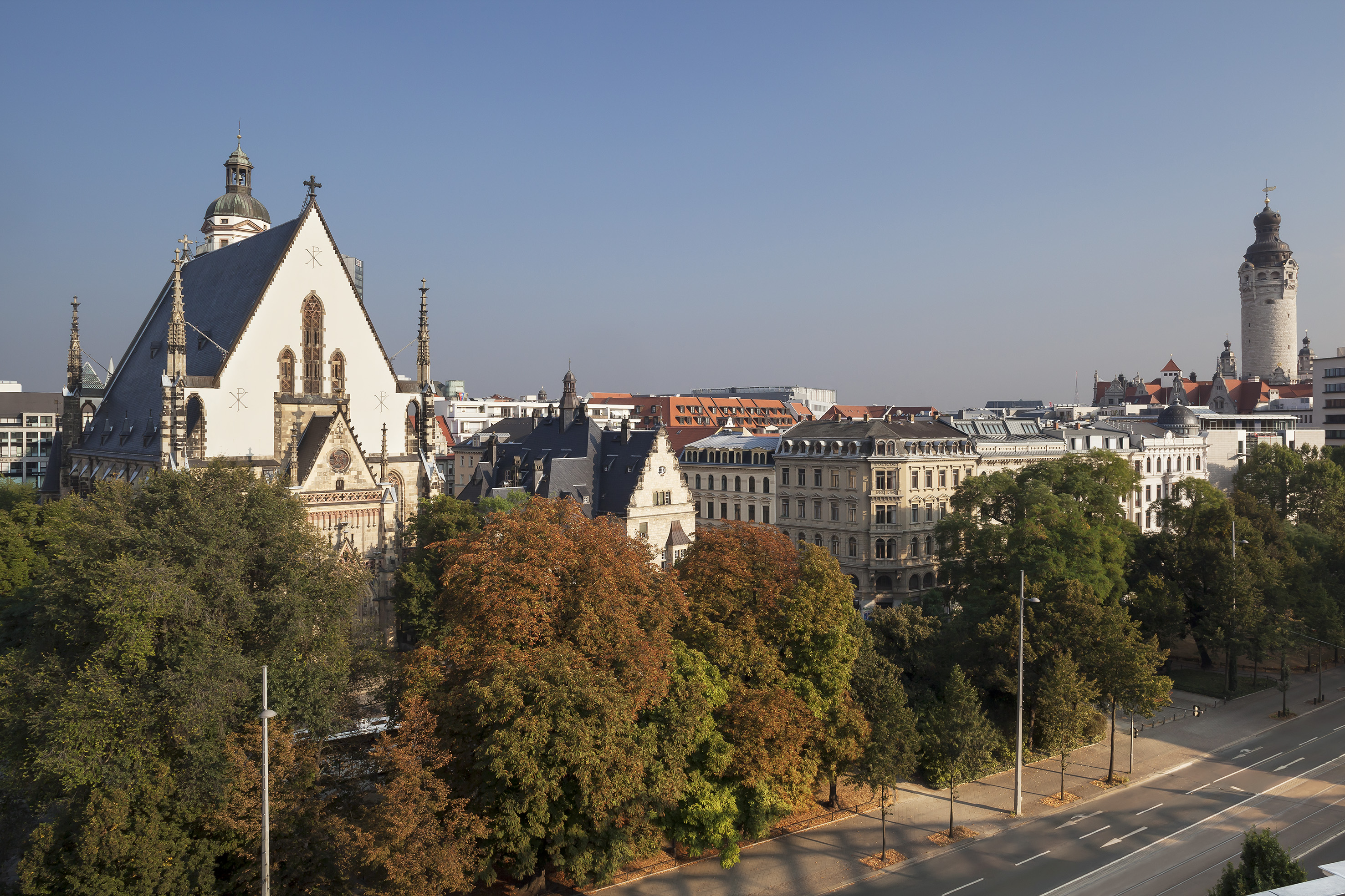 Leipzig cityscape featuring Paulinum, historic architecture, and autumn trees.