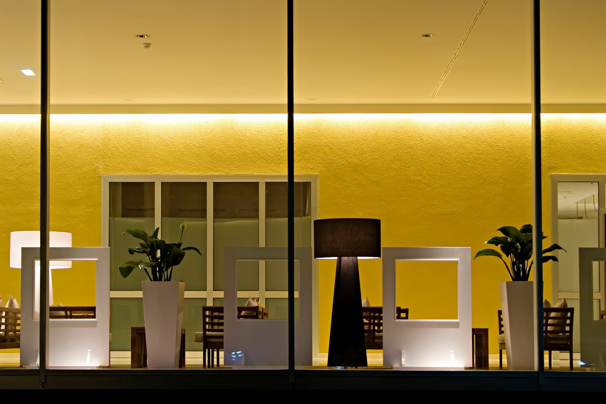 a room with a window with a few white vases and a lamp