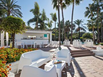 a white chairs and tables outside with palm trees