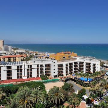 a large white building with palm trees and a beach