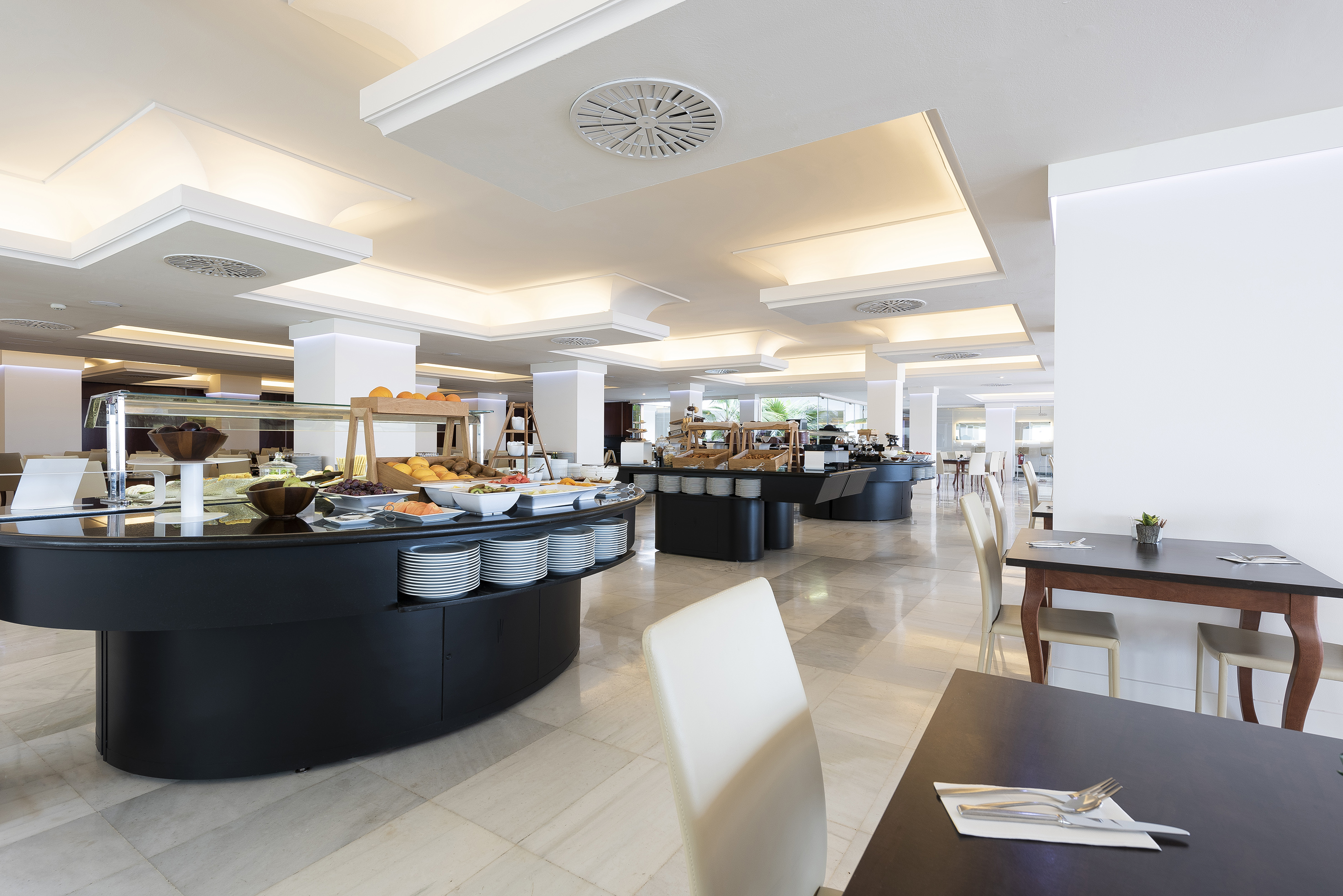 Modern hotel buffet restaurant with fresh food and prepared dining tables.
