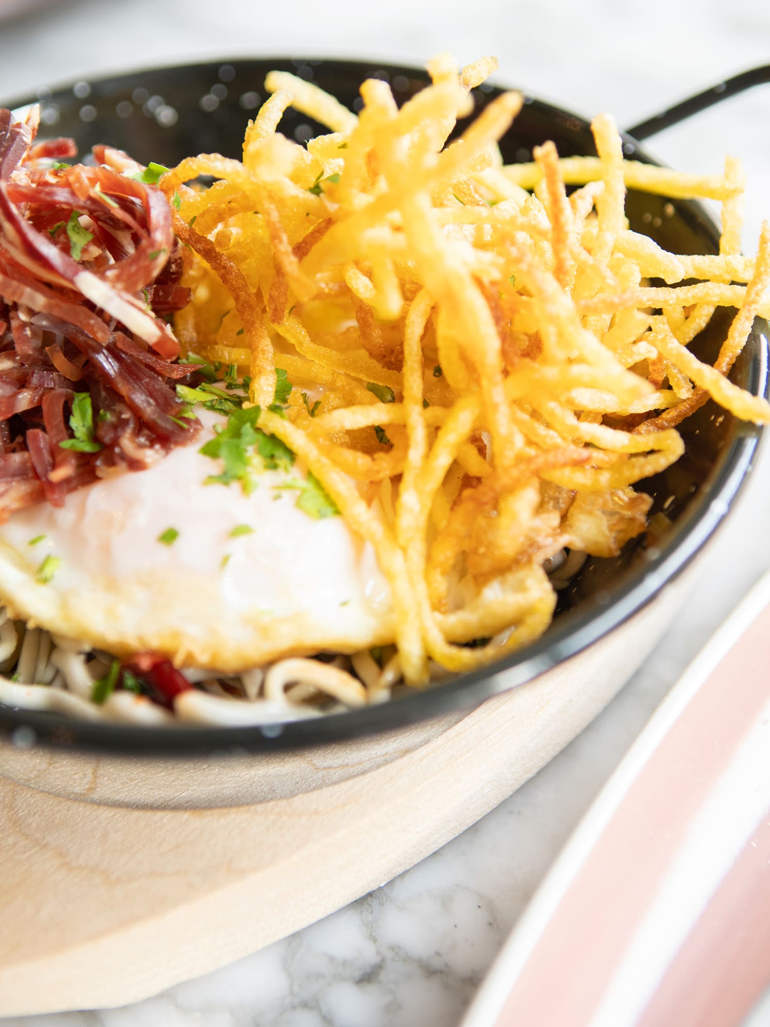 a bowl of noodles with a egg and some meat