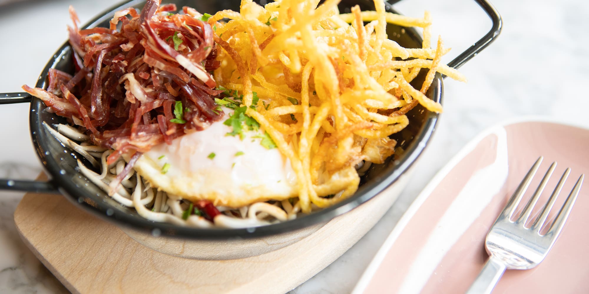 a bowl of noodles with a egg and some meat