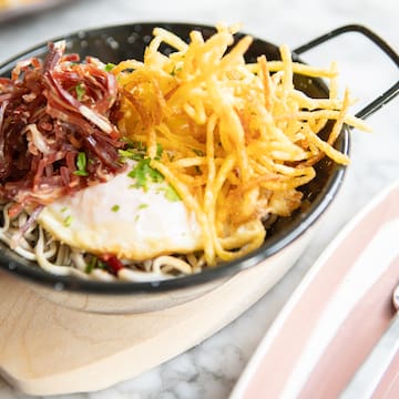 a bowl of noodles with a egg and some meat