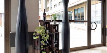 a wine rack with plants and a tall vase in front of a glass door