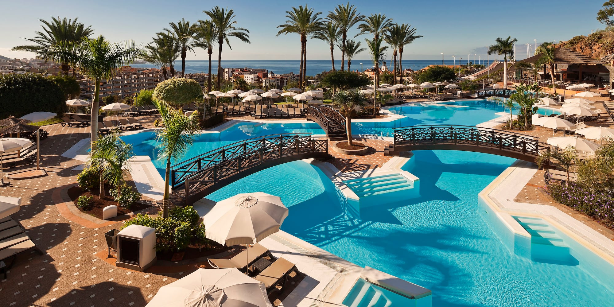 a swimming pool with umbrellas and palm trees