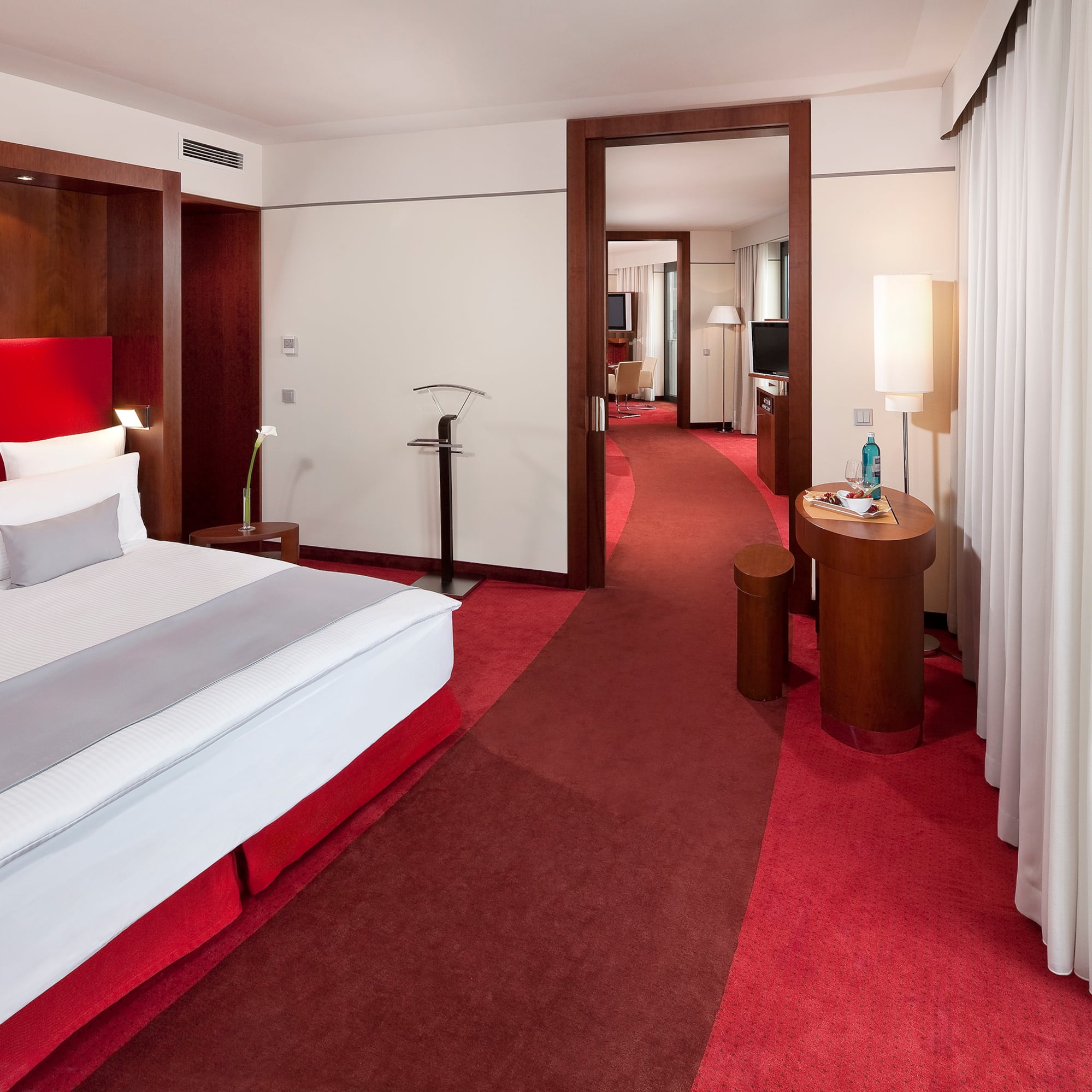 a hotel room with red carpet and white bed