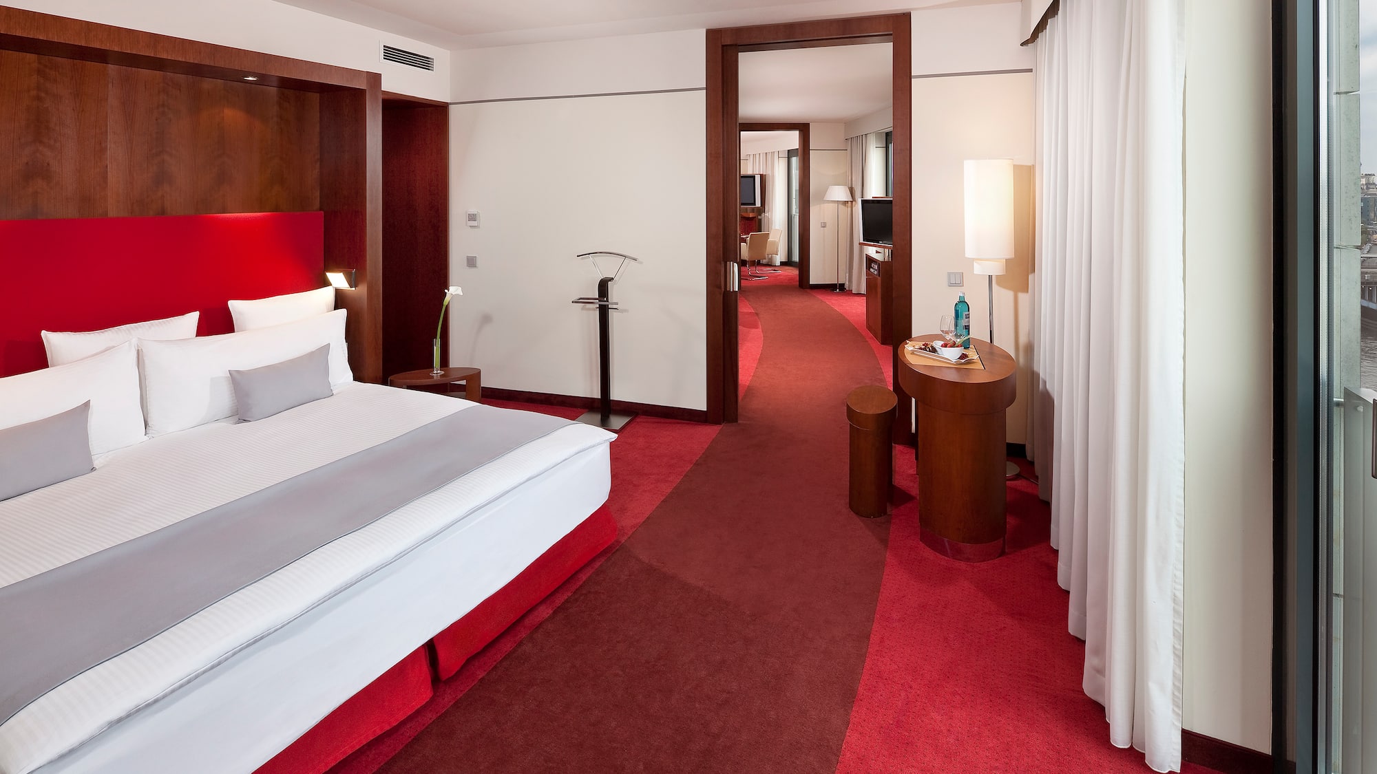 a hotel room with red carpet and white bed